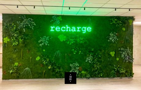 pared de musgo tipo jungla Recharge logo con luz detras
