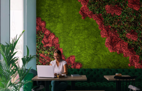 Mooswand mit Hortensien und Pflanzen in einem Caffee und im Vordergrund sitzt eine Frau 